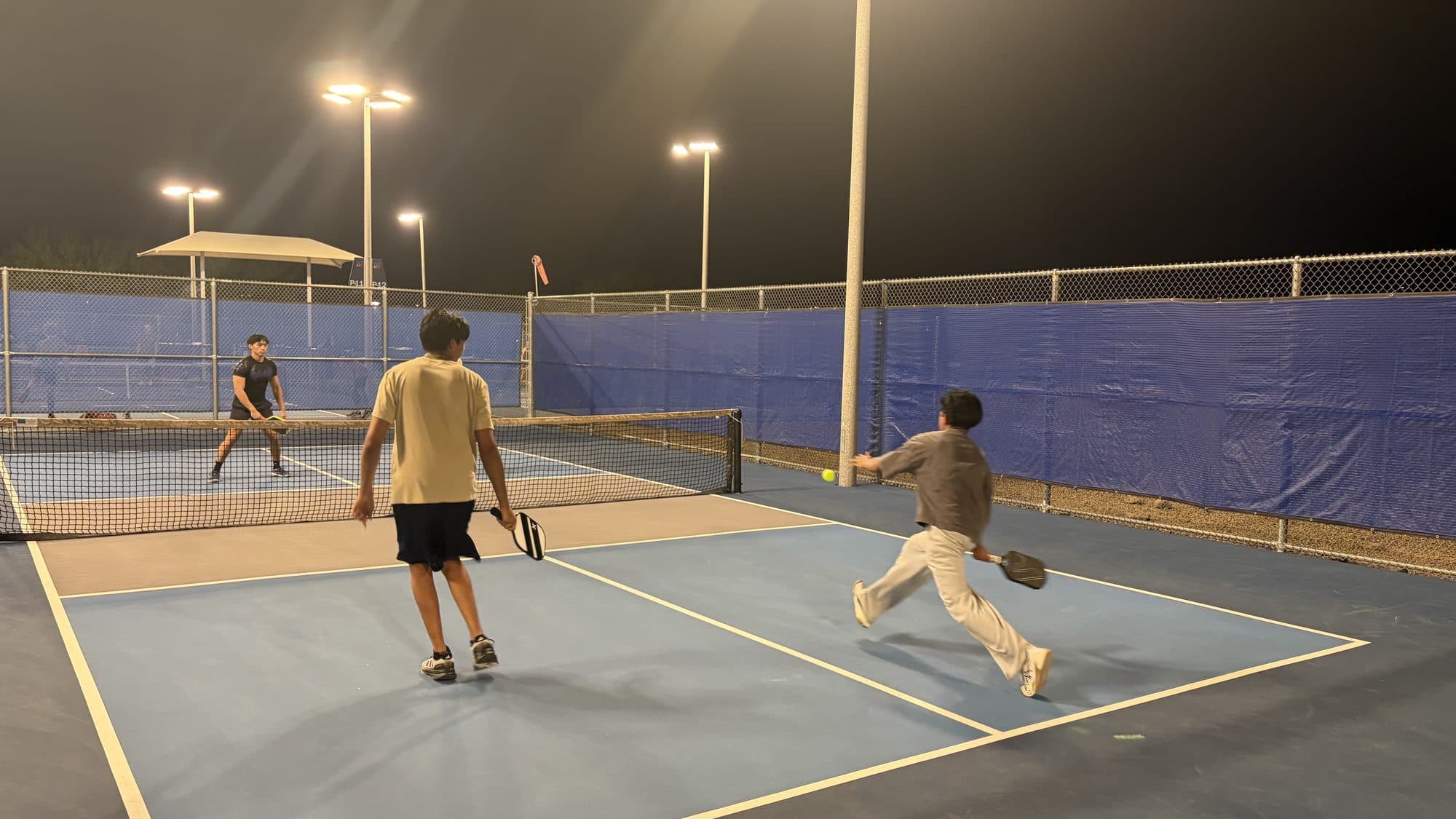 A player stretching wide to return a ball near the sideline during a doubles point